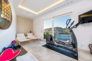 Kleiner Fitnessraum mit Cardiogeraet, kleines Hanteln, zwei Liegen und Meerblick