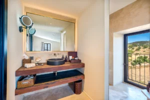 Badezimmer mit Waschbecken, Holz- und Steinelementen und Fenster.