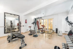 Privates Fitnessstudio mit Hanteln, Hantelbank, Fahrrad und Ganzkörpermaschine.