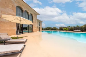 Blickwinkel der anderen Seite auf die Rückseite der Villa mit Teilblick auf den Pool und Liegestühle