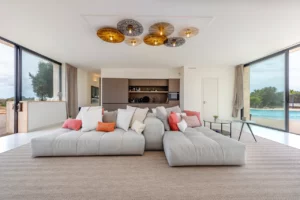 Frontalblick auf das Wohnzimmer mit gemütlichen Sofa und Küchenzeile im Hintergrund.